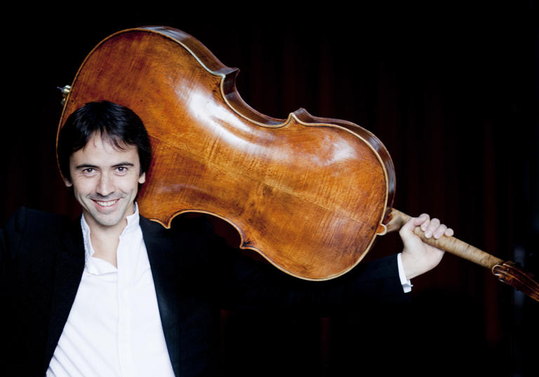 Jean Guihen Queyras holding a cello over his head