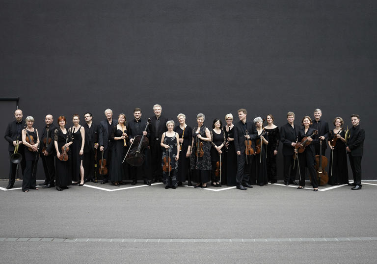 Freiburg Baroque Orchestra standing black wall