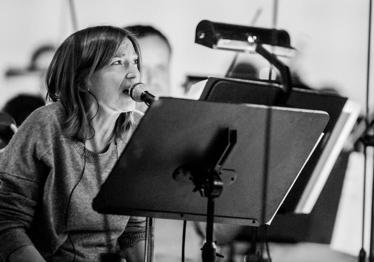 Beth Gibbons singing into a microphone, with a music stand and headphones
