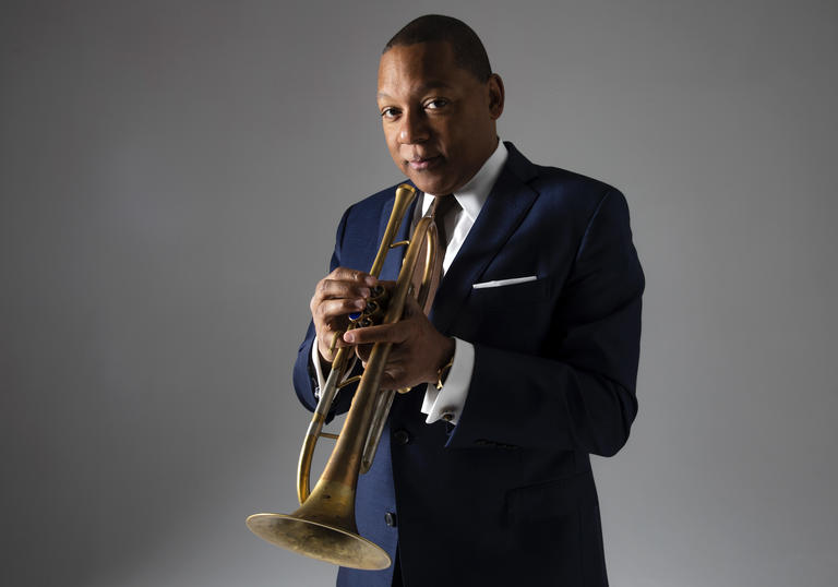 Wynton Marsalis wearing a suit, holdin his trumpet