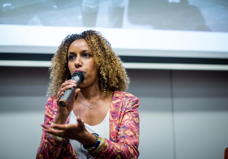 a woman stands with a microphone doing a talk