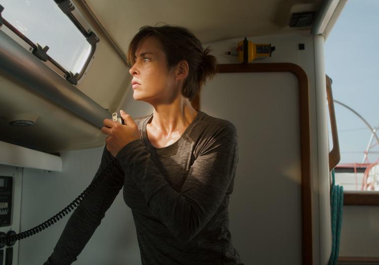 A woman in a grey top on the radio of her boat.