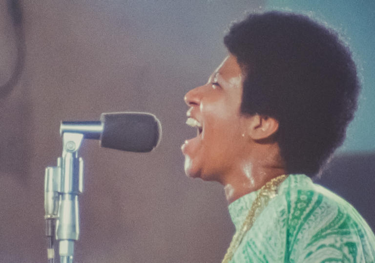 Aretha Franklin singing in green