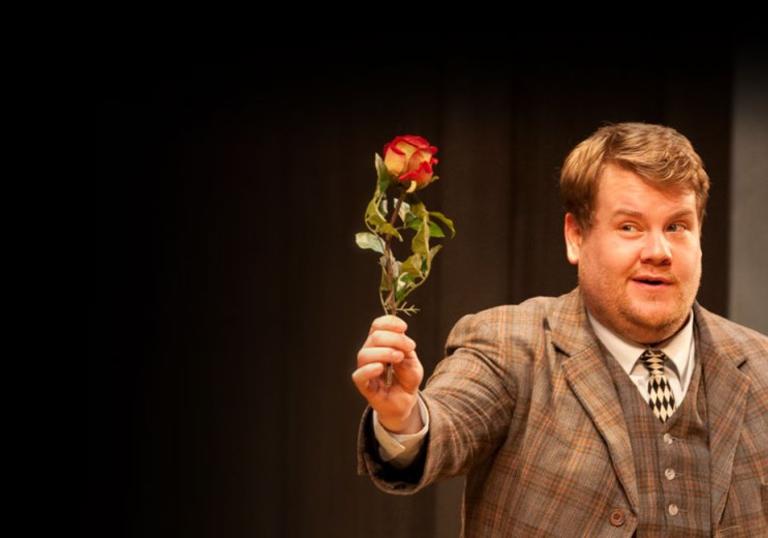 James Corden in a tweed three-piece holding a single flower