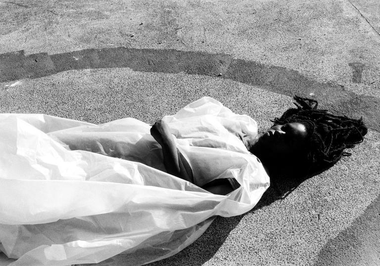 Moor Mother lying on a concrete floor