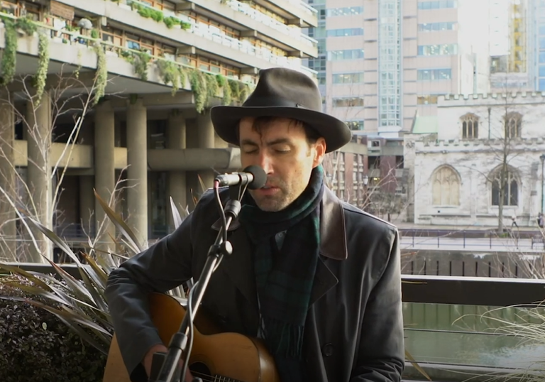photo of andrew bird with a black hat by the barbican lakeside