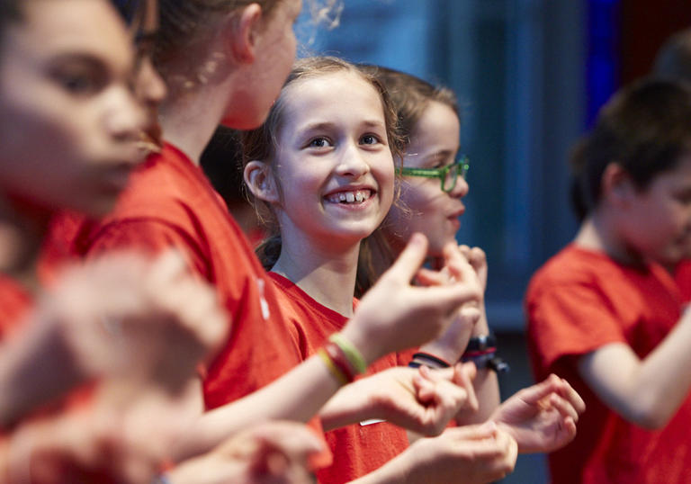 Members of the LSO Discovery Junior Choir sing in red t-shirts