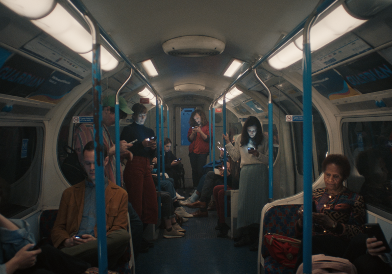 Group of people on underground train all looking at their phones