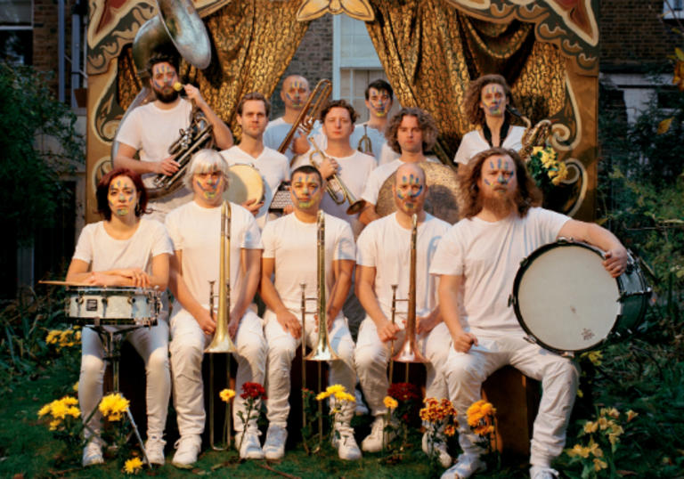 Hackney Colliery Band sat in two lines with their instruments