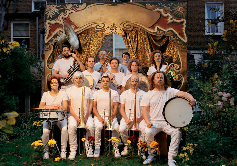 Hackney Colliery Band sat in two lines with their instruments