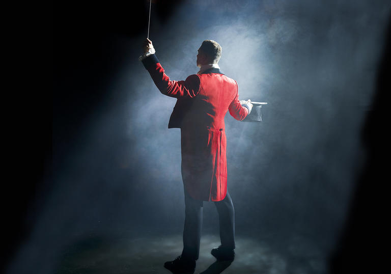 A circus ringmaster standing in a spotlight