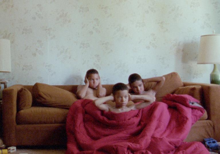 Boys sitting on a sofa covering their ears