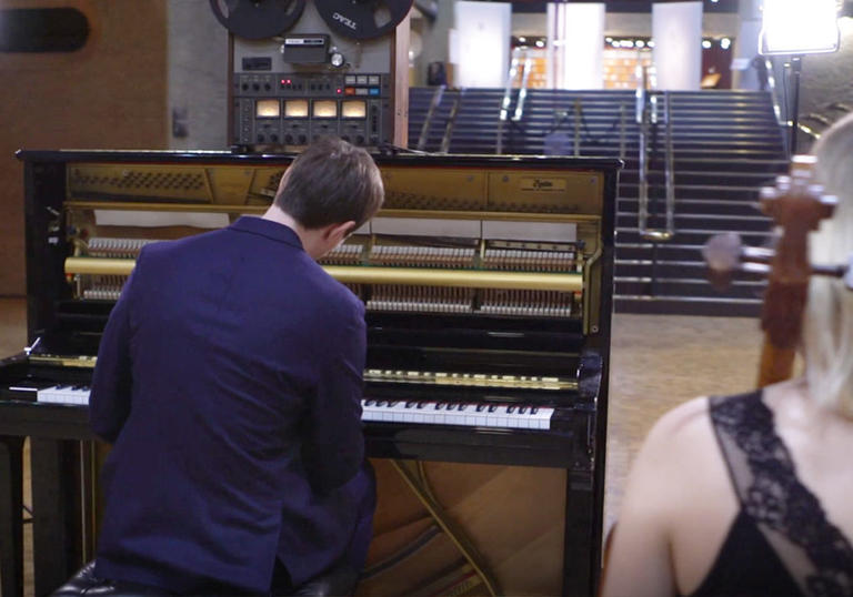 photo of erland cooper in front of a piano in the barbican foyer