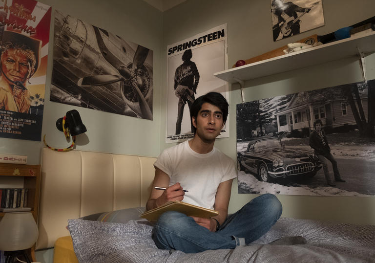 Viveik Kalra sitting on his bed surrounded by Bruce Springsteen posters