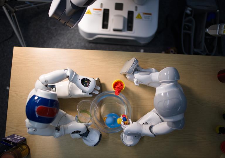 An aerial image of two toy robots sitting on a wooden table