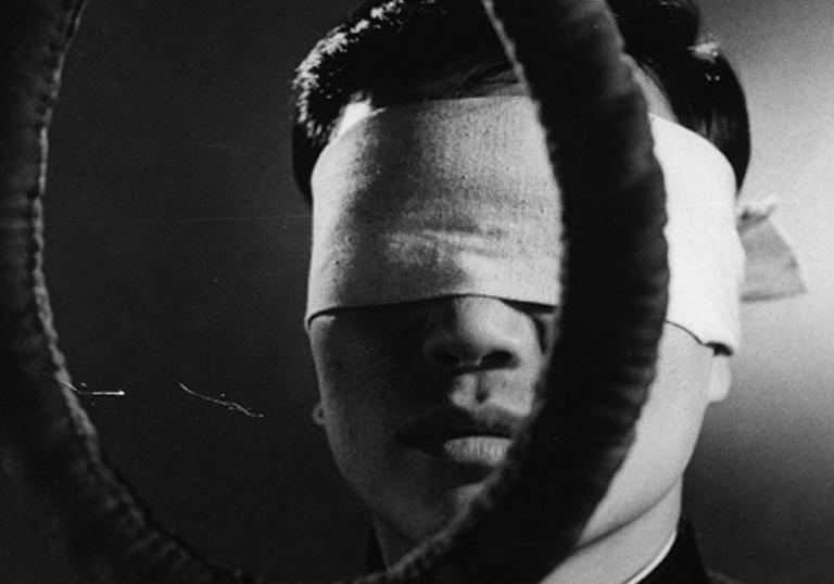 blindfolded man standing behind a noose