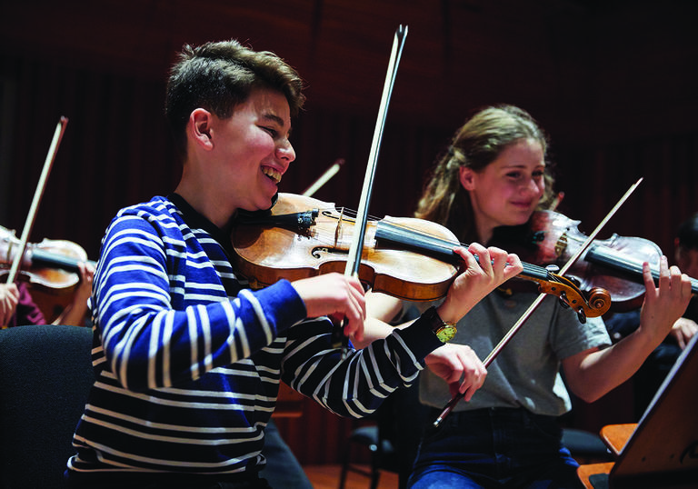 Smiling violinists playing in Junior Guildhall ensemble