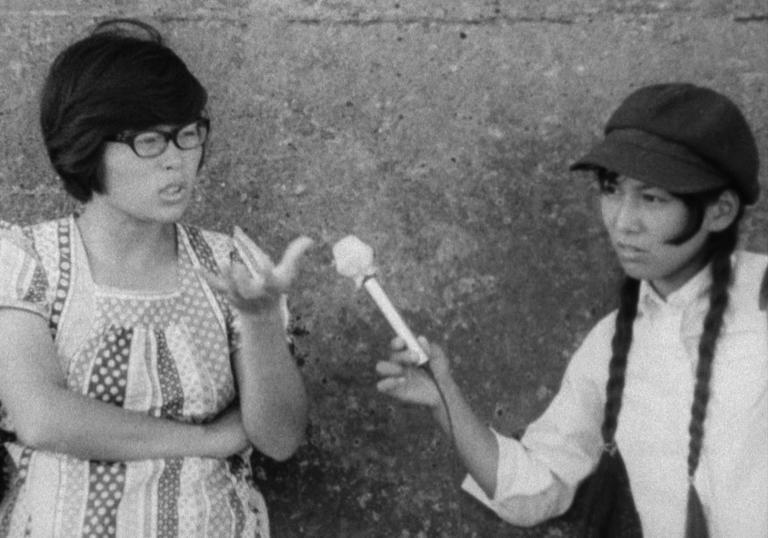 one women interviewing another in front of a wall