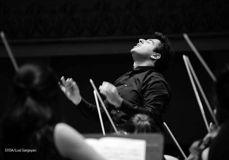 Sergey Smbatyan conducting surrounded by violin bows