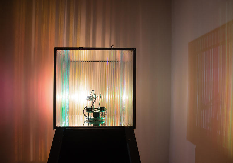 An image of a lamp inside a perspex cube casting florescent light over the room