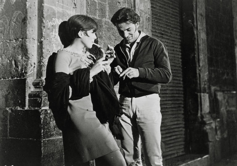 man and woman leaning against a wall at night