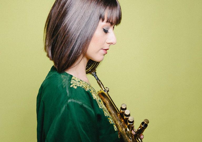 Yazz Ahmed holding trumpet against a green background