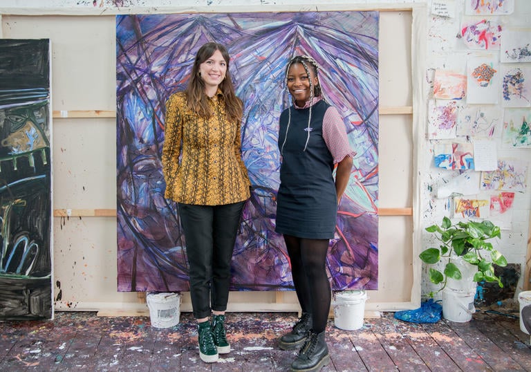 Two women standing in front of a purple painting