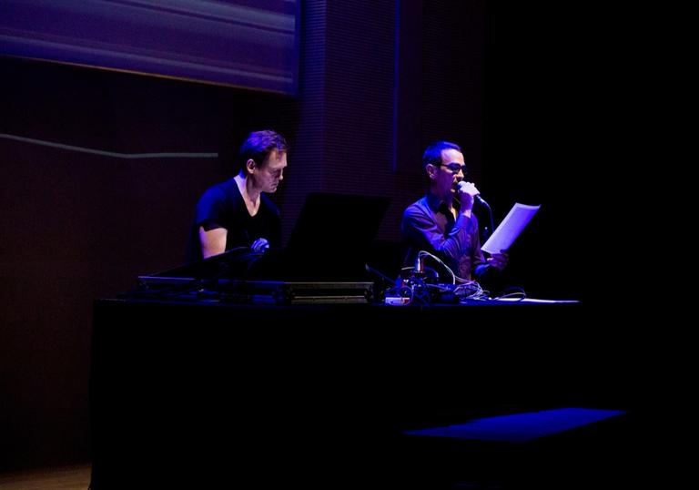 Alva Noto and Anne-James Chaton performing with laptops and a microphone