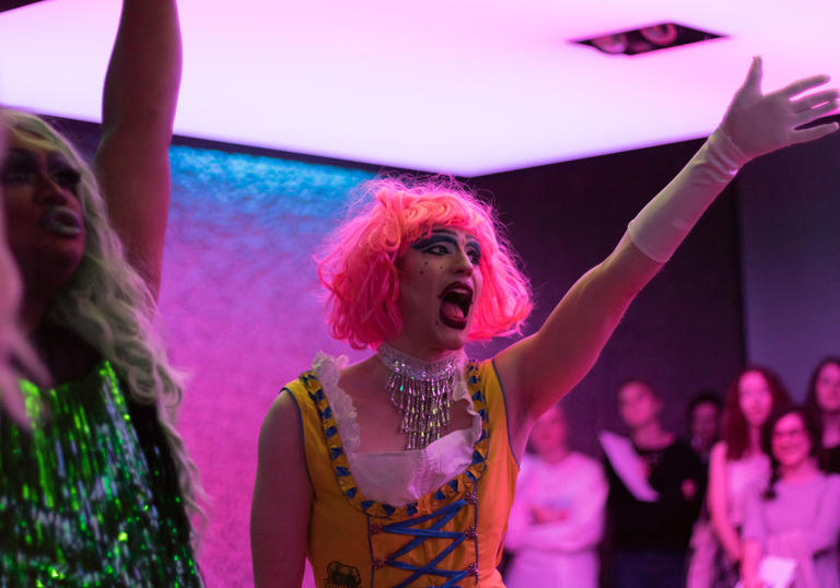 A Drag Queen with a pink wig singing