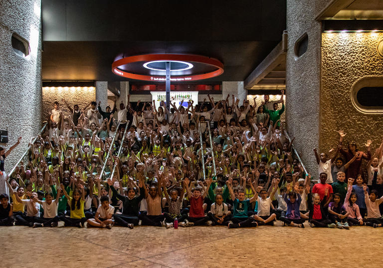 Large group of children seating and cheering on some steps in the Barbican