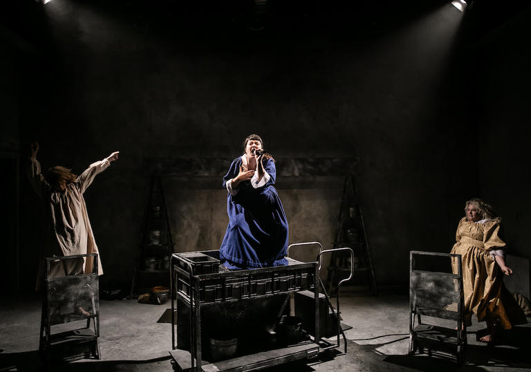 three women in ragged dresses dance and sing 