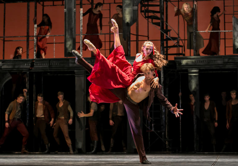 dancer is red dress is held up by a male dancer with his shirt open