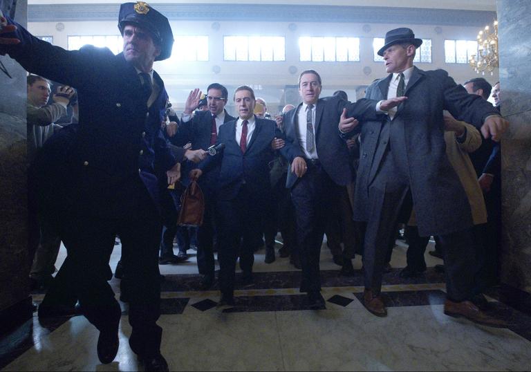 Al Pacino and Robert De Niro are escorted through a lobby by police in Martin Scorsese's The Irishman