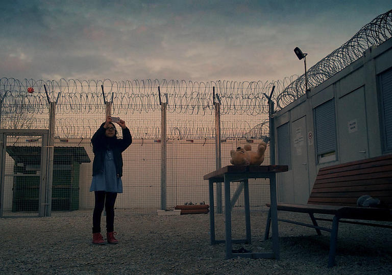a person holding a phone in front of barbed wires