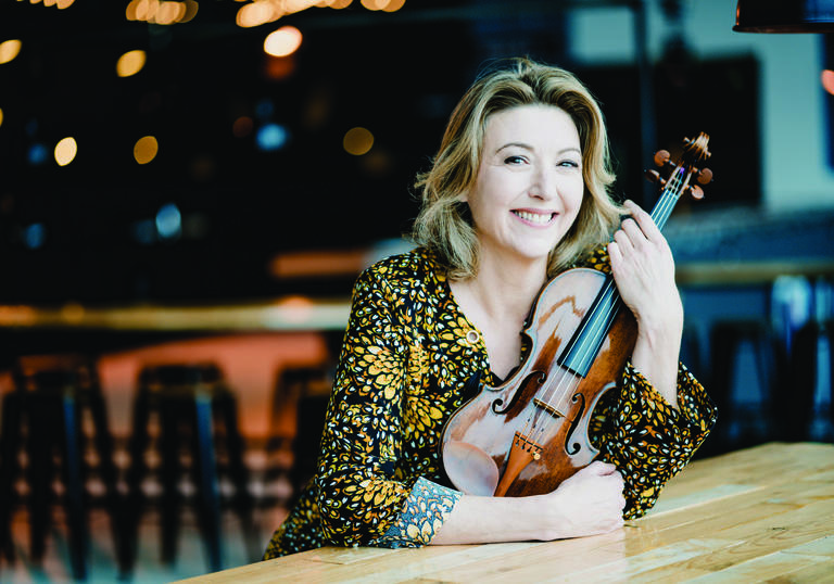 Candida Thompson sitting at table holding violin