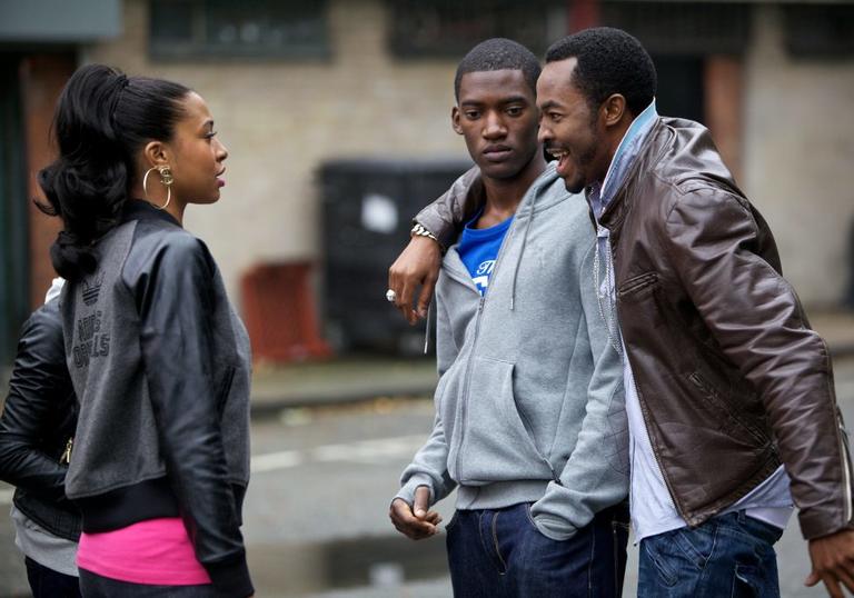 Two men and a woman chat on the street in Destiny Ekaragha's film Gone Too Far!