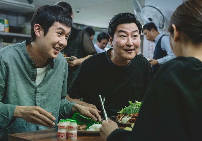 father and son smiling up at someone across the dinner table