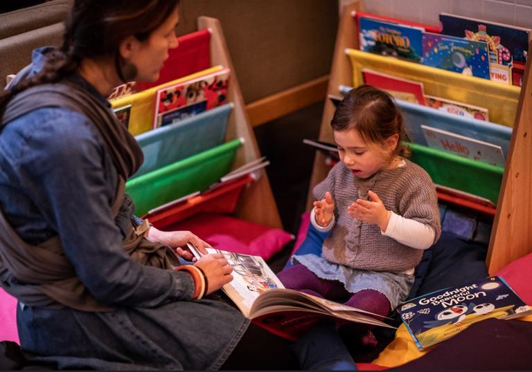 a young girl reads a picture book with her mum