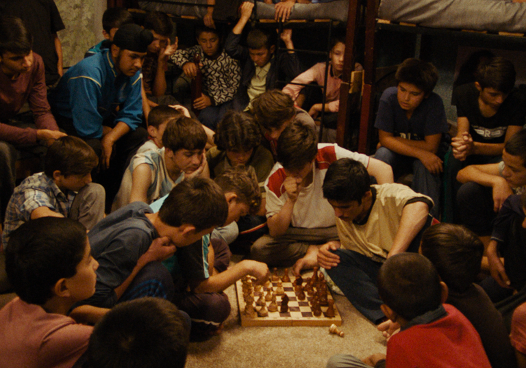 A large group of young boys play chess in The Orphanage