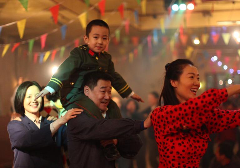 little boy on his father's shoulders dancing