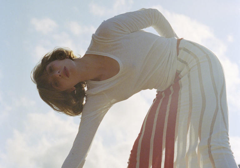 photo of Aldous Harding leaning over with sky in the backgrouond