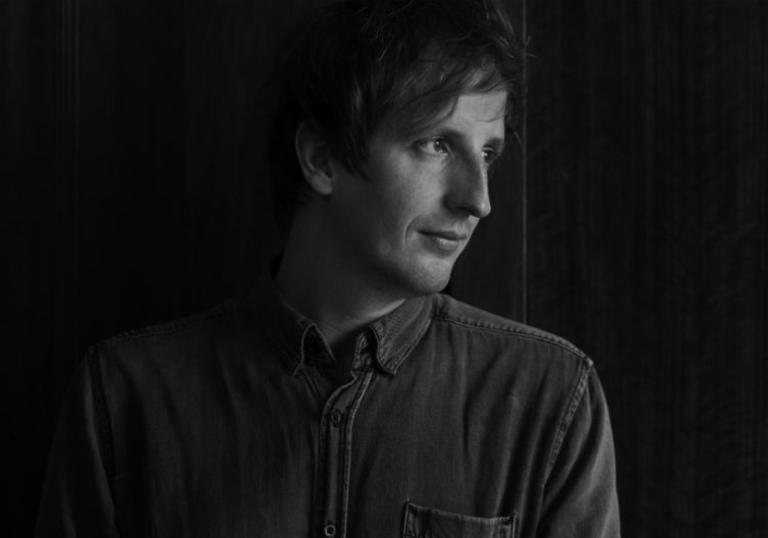 black and white photo of Christian Löffler showing his head and shoulders. His face is turned to one side