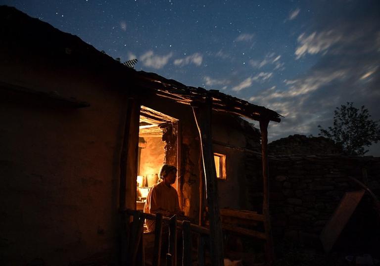 woman sitting in the doorway of her house at twilight