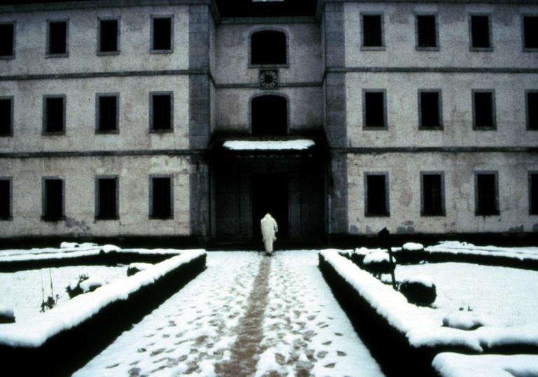 priest walking in the snow into a large building