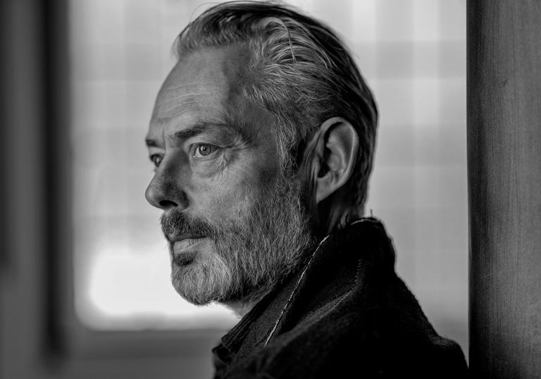 A black and white portrait of Mark Padmore gazing into the distance 