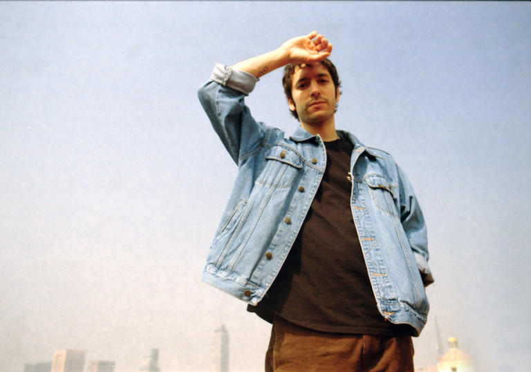 outdoor photo of Nicola Cruz. He is dressed casually,with a city landscape in the background