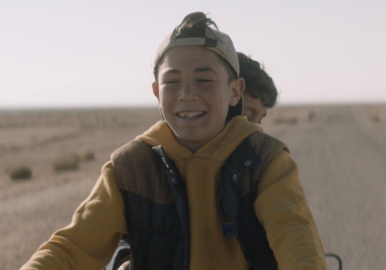 two boys on a motorbike riding along a road