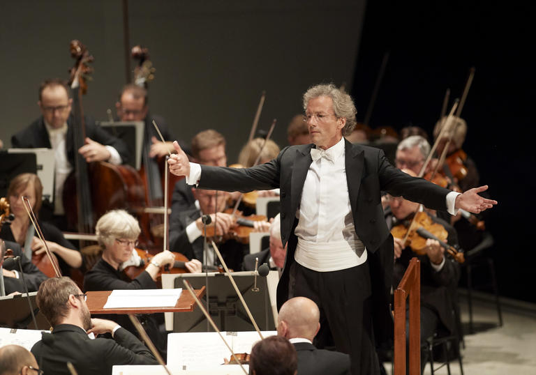An image of Franz Welser-Möst conducting the Cleveland Orchestra with great enthusiasm