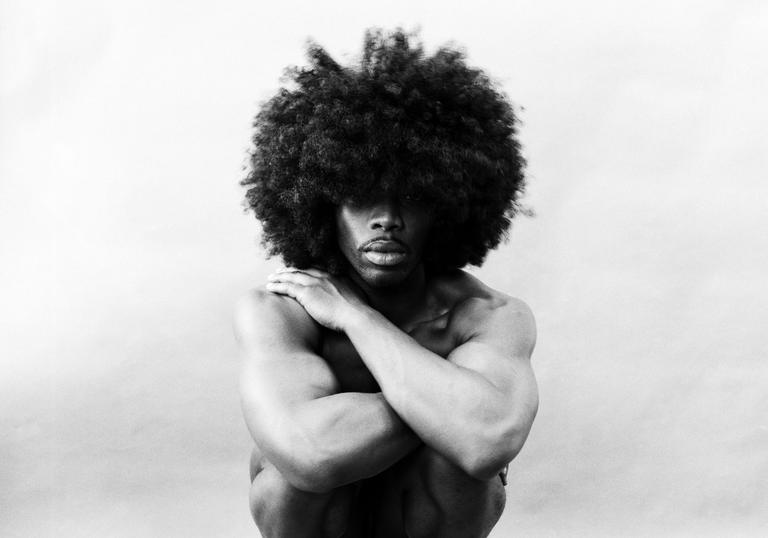 A black and white photograph of a crouched, naked man taken by photographer Rotimi Fani-Kayode