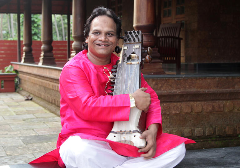 Sarwar Hussain Khan sitting crossed-legged with his sarangi instrument